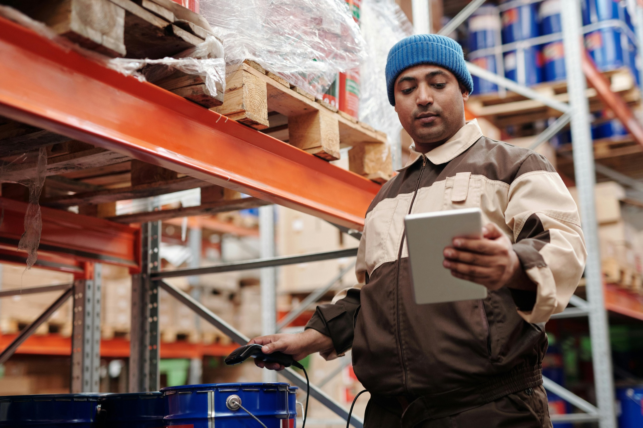Warehouse staff member checking stock and shipment details on a tablet in a storage aisle